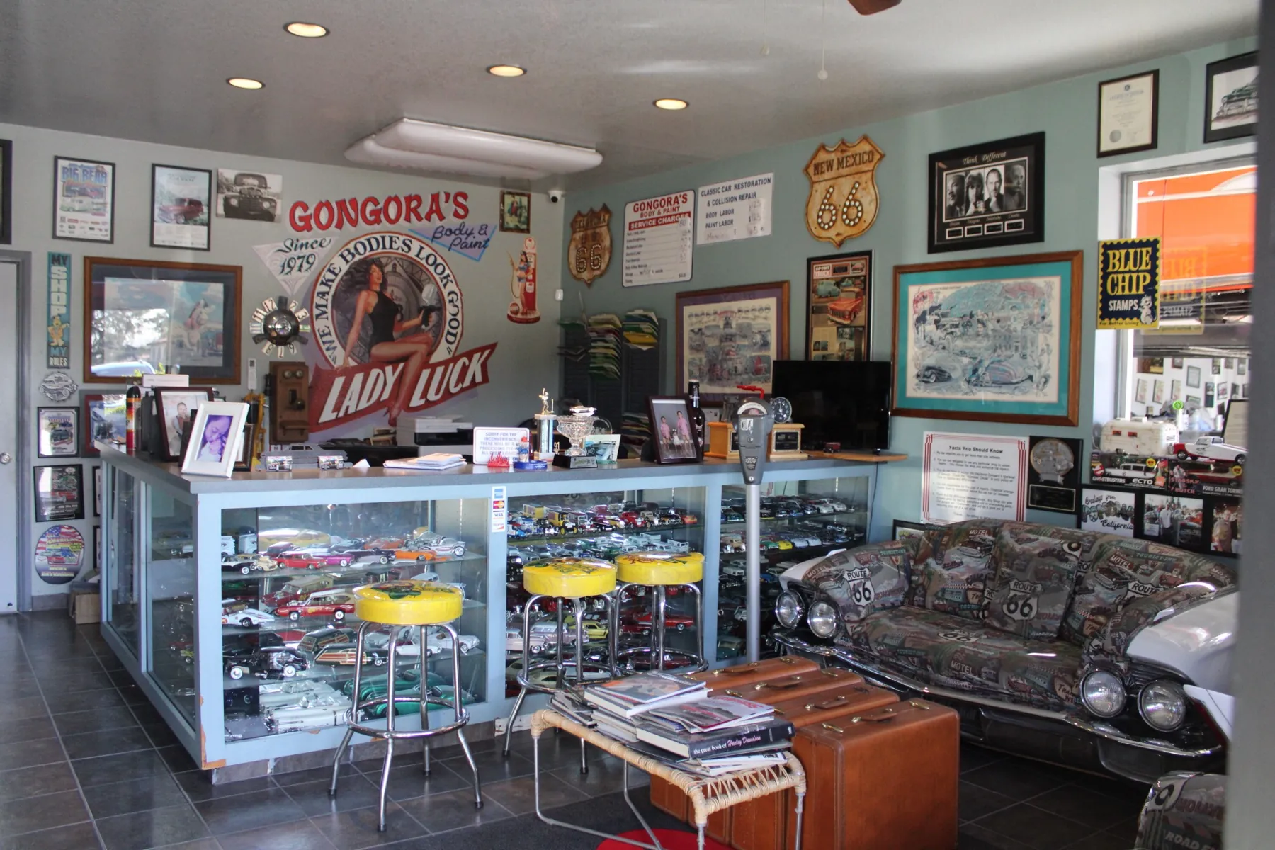 Gongora’s front office: the Lady Luck sign, a glass case of model cars, yellow stools and a couch built from a classic car